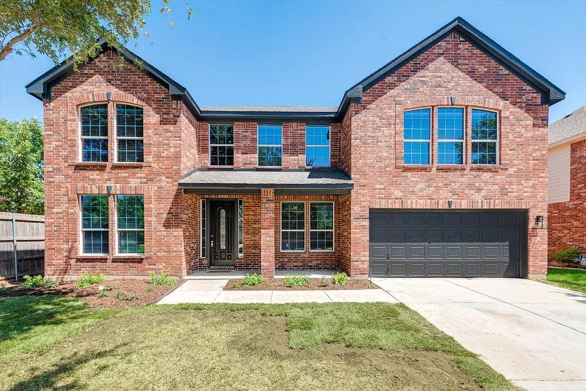 Two-story red-brick home with a covered entry and double garage.
