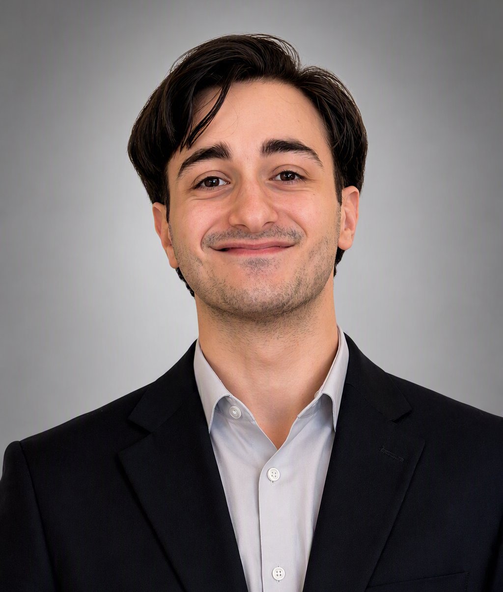 Steven Stasio in a black suit jacket and white shirt against a gray background.