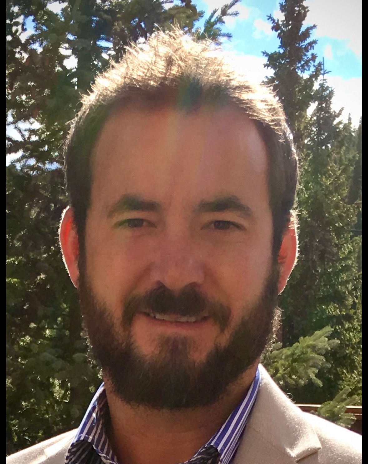 Trent Smart, a bearded man in a tan jacket outdoors.