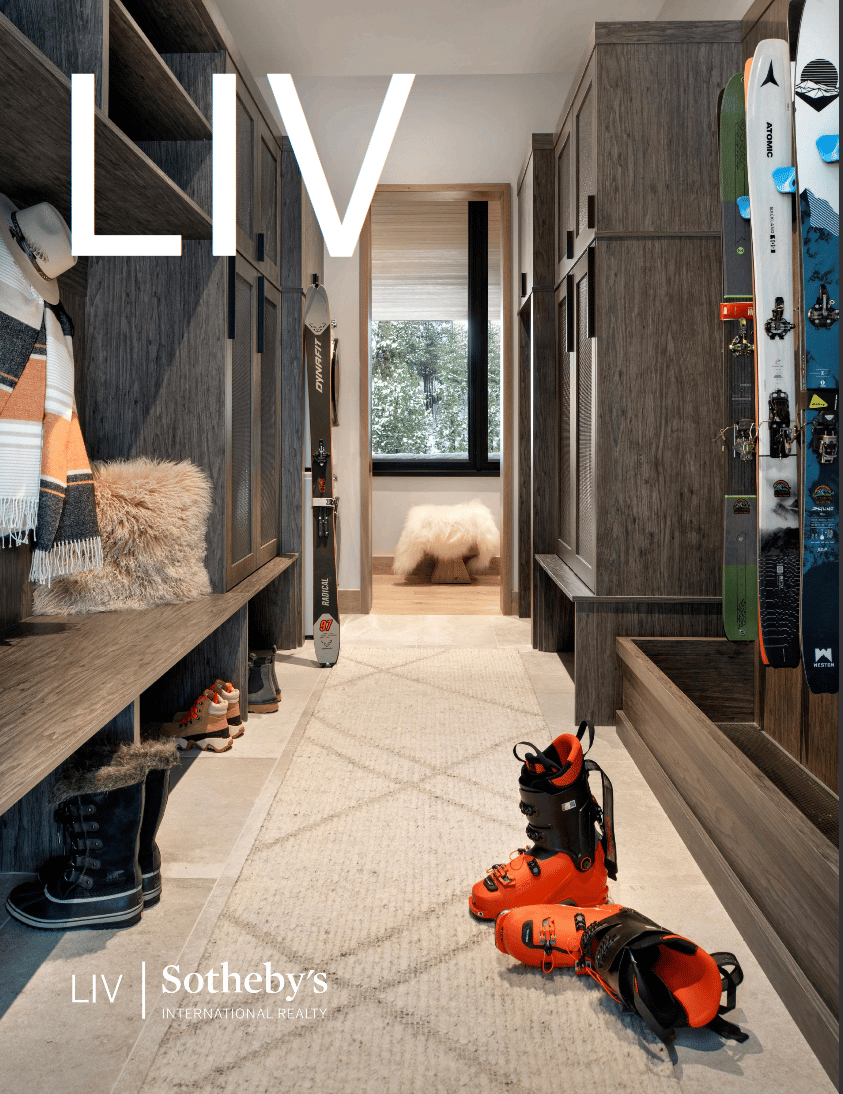 Modern ski room with dark wood cabinetry, wall-mounted skis, and bright orange ski boots.
