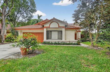 Single-story stucco home with a red tile roof, arched facade detail, and landscaped front lawn.