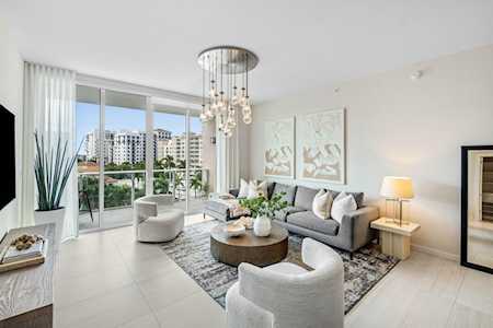 Bright living room with sliding glass doors, a gray sofa, and a sculptural chandelier.