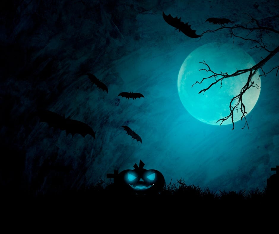 Glowing jack-o'-lantern, flying bats, and bare branches silhouetted against a blue full moon.