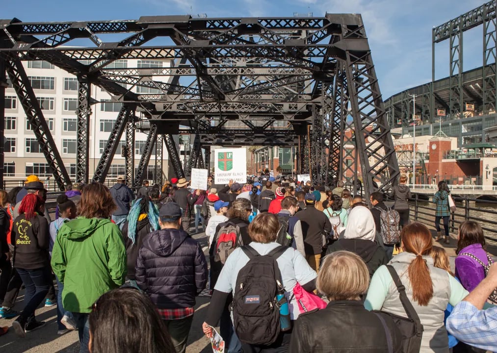 Marchers crossing the Lefty O'Doul Bridge near Oracle Park, holding a Union of Black Episcopalians sign.
