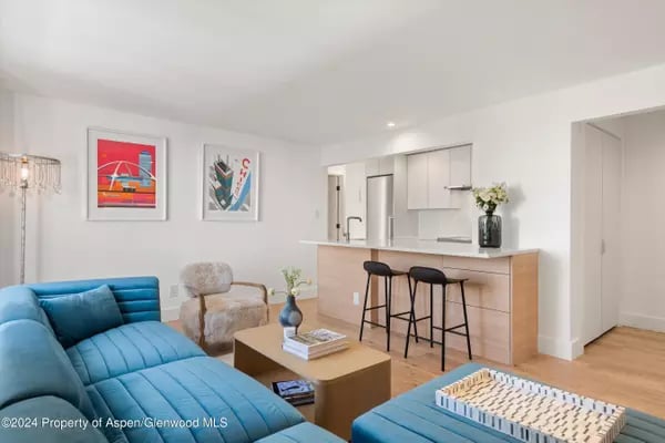 Open-plan living room with a blue sectional sofa and kitchen breakfast bar.