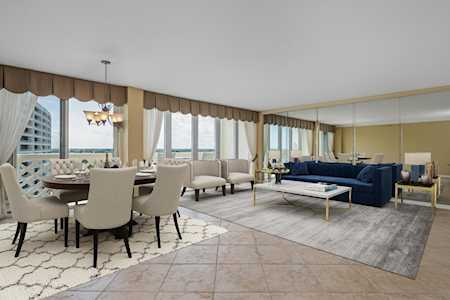 Open-plan living and dining room with a blue sofa and water visible through large windows.