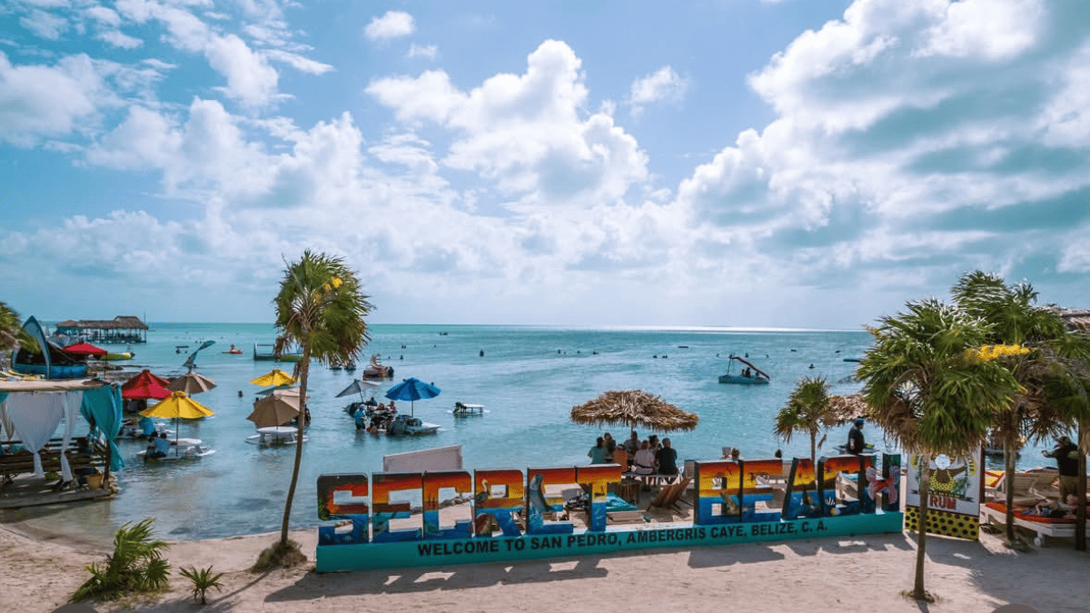 Welcome sign on the beach with palm trees and water in the background
