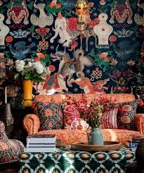 Eclectic living room with a colorful patterned sofa, figure-covered wallpaper, and a low coffee table.