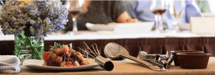 Dining table with a plate of food, wine glasses, utensils, and flowers