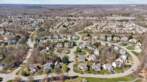 Aerial view of a suburban neighborhood with curving streets, detached homes, and leafless trees.