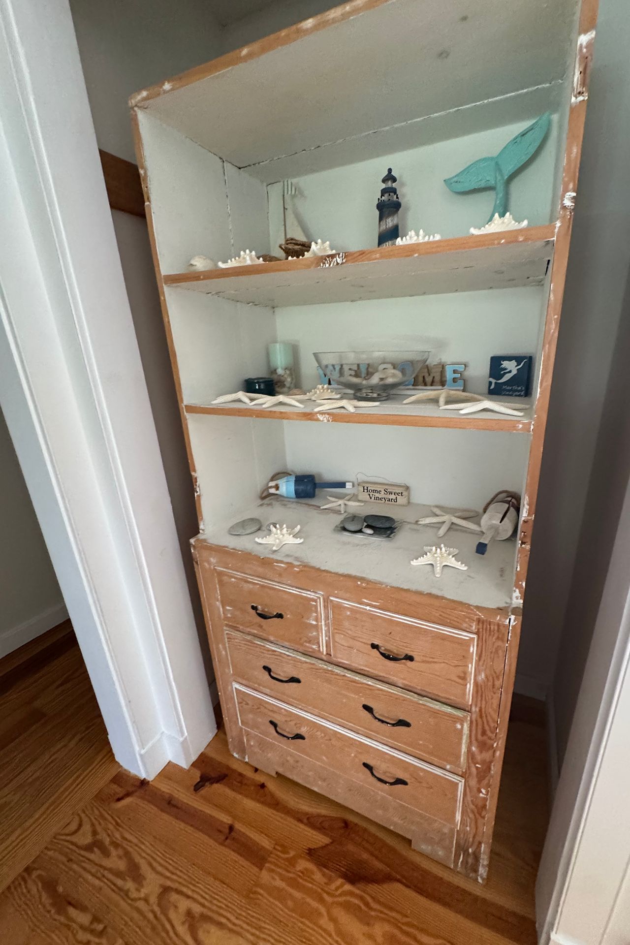 Wooden built-in shelves and drawers decorated with seashells, a lighthouse figurine, and Vineyard keepsakes.