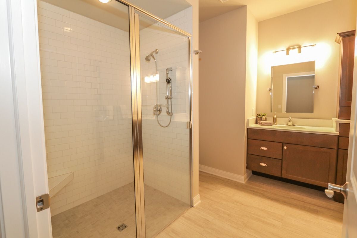 Bathroom with a glass-enclosed subway-tile shower and dark wood vanity.