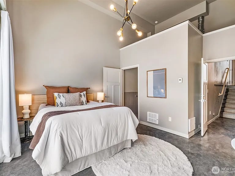 Staged bedroom with a white bed, shag rug, and modern pendant light.