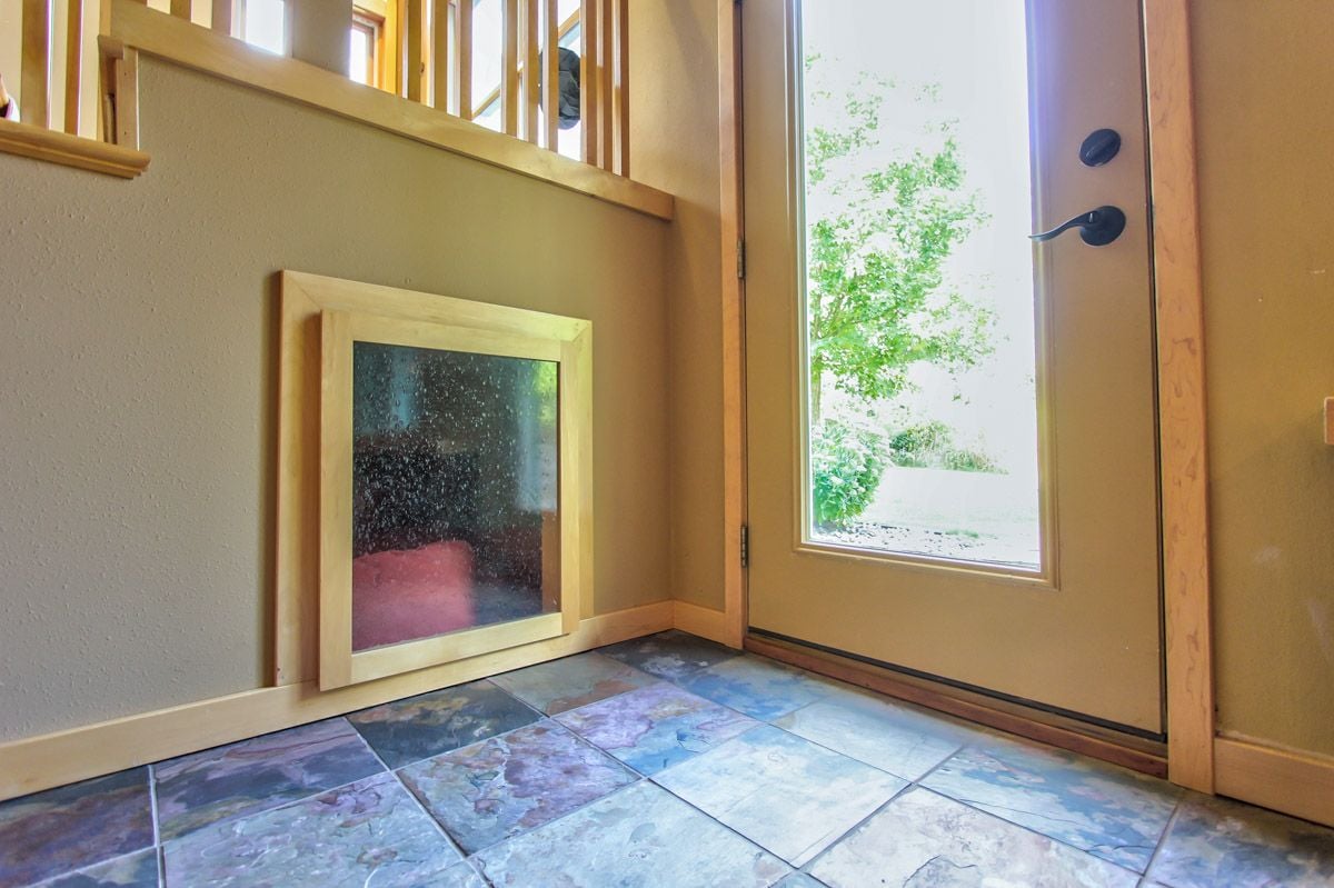 Entryway with a glass-panel wood door, low pet door, and colorful stone tile floor.