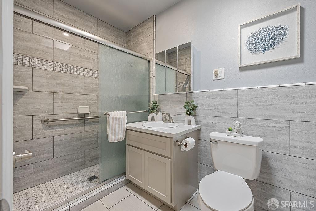 Bathroom with a gray-tiled walk-in shower, glass enclosure, and light vanity.