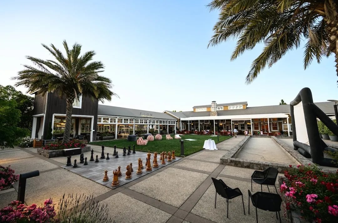 Panoramic view of the Town Square at Carneros Resort and Spa, showing the outdoor movie setup with the FARM Restaurant pavilion glowing warmly nearby.