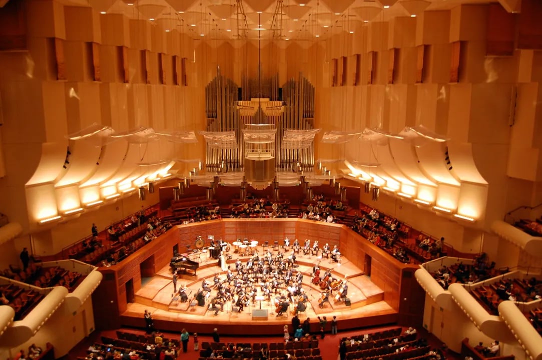 Interior view of the San Francisco Symphony performing on stage beneath the grand pipe organ and acoustic canopy at Davies Symphony Hall.