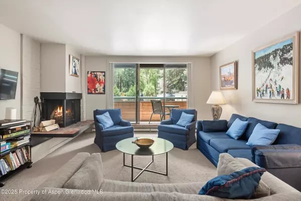 Living room with blue seating, a fireplace, and sliding doors opening to a balcony.