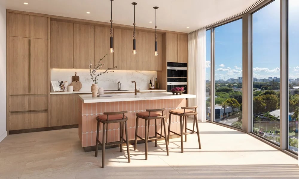 Modern kitchen with a pink-tiled island and wide windows overlooking greenery and the Miami skyline.