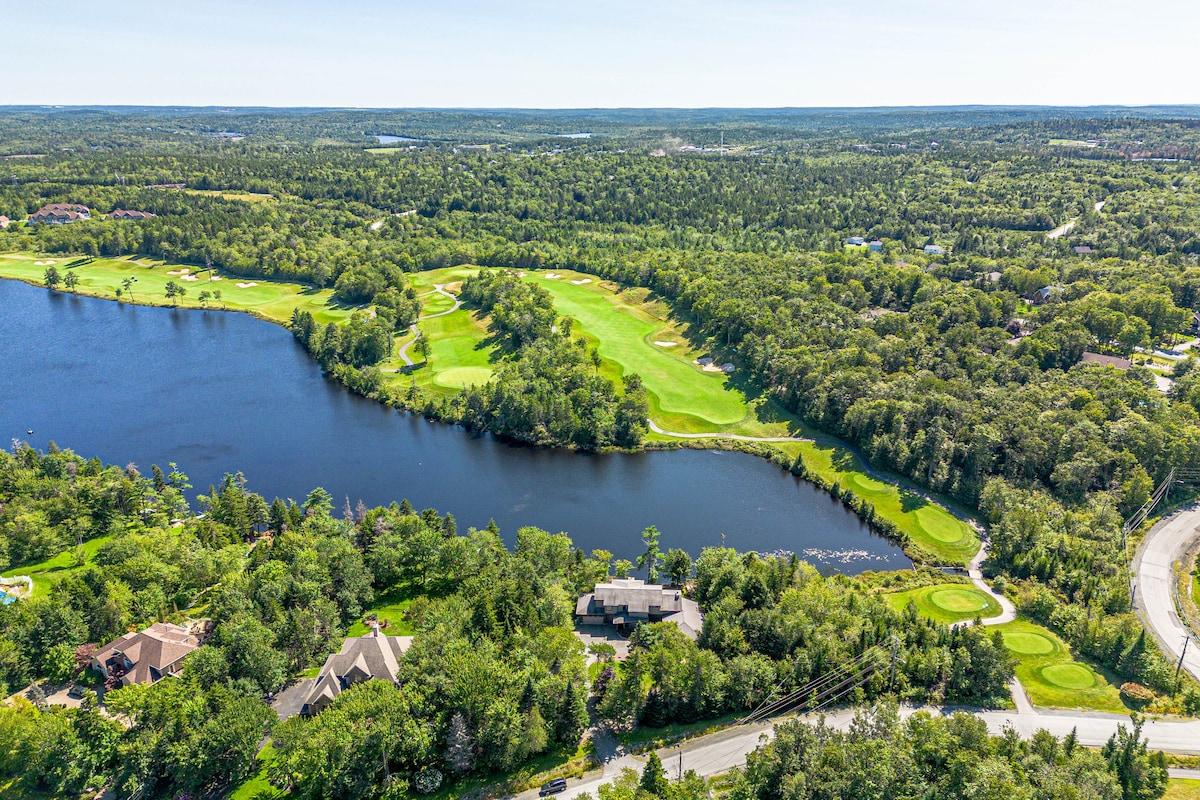Aerial view of a Hammonds Plains golf course beside a lake, surrounded by woods and homes.