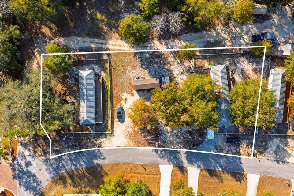 Aerial view of two homes within a white-outlined parcel beside a paved road.