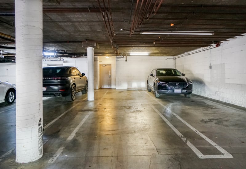Underground parking garage with marked spaces and parked cars.