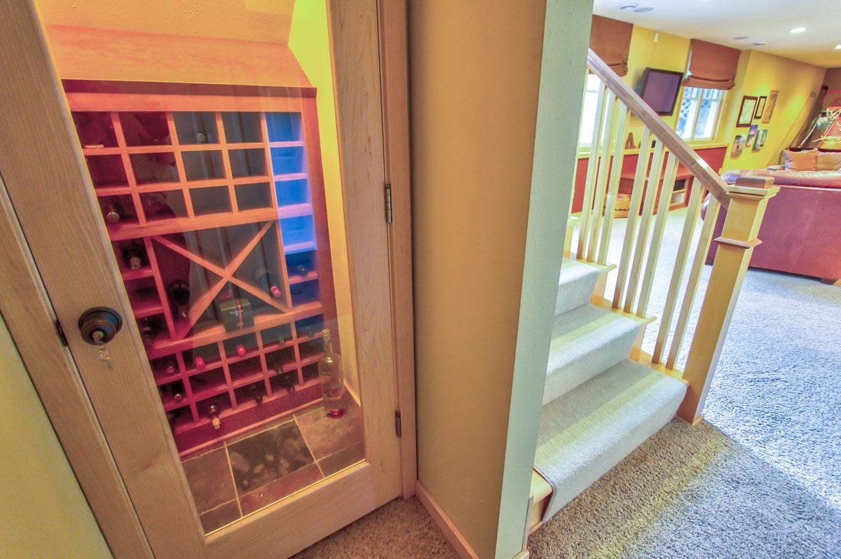 Built-in wine cellar beside carpeted stairs leading to a living area.