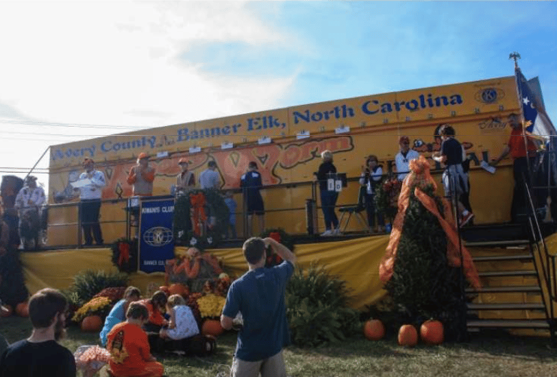 Fall festival in Banner Elk, North Carolina, with a decorated stage, pumpkins, and visitors.