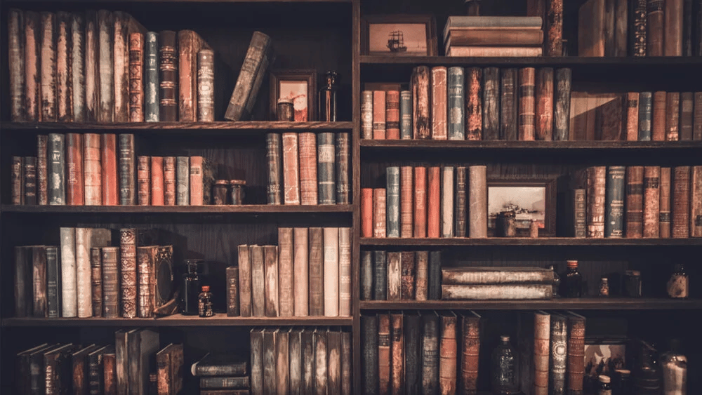 Dark wooden bookcase filled with antique books and a few framed pictures.