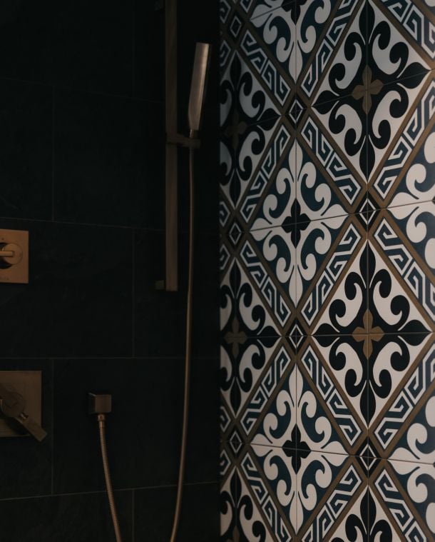 Bathroom shower with geometric patterned tile and a handheld showerhead.