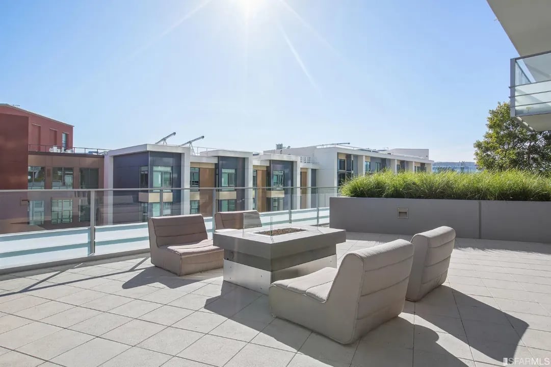 Arden Residences sunny rooftop deck with a fire pit and outdoor seating.