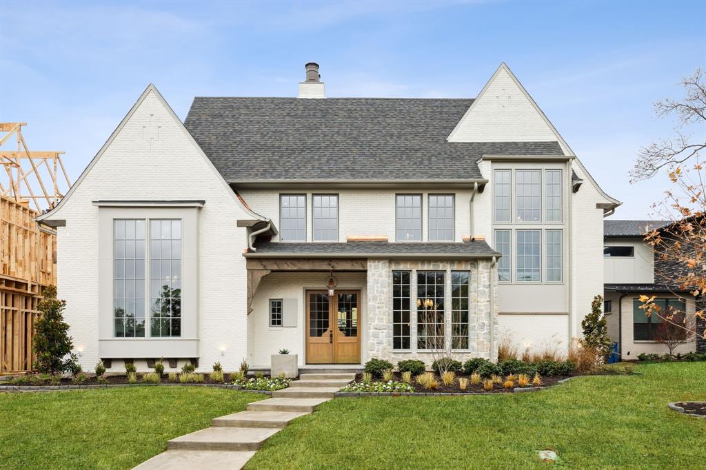 White-brick home with steep gables, tall windows, and a stone-accented front entrance.