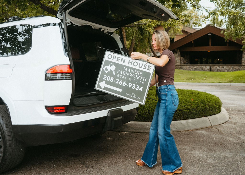 Mandie Farnworth loads an open house sign into her SUV outside a home.