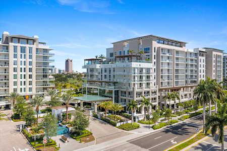 Modern condominium buildings with glass balconies, landscaped grounds, and palm-lined streets.