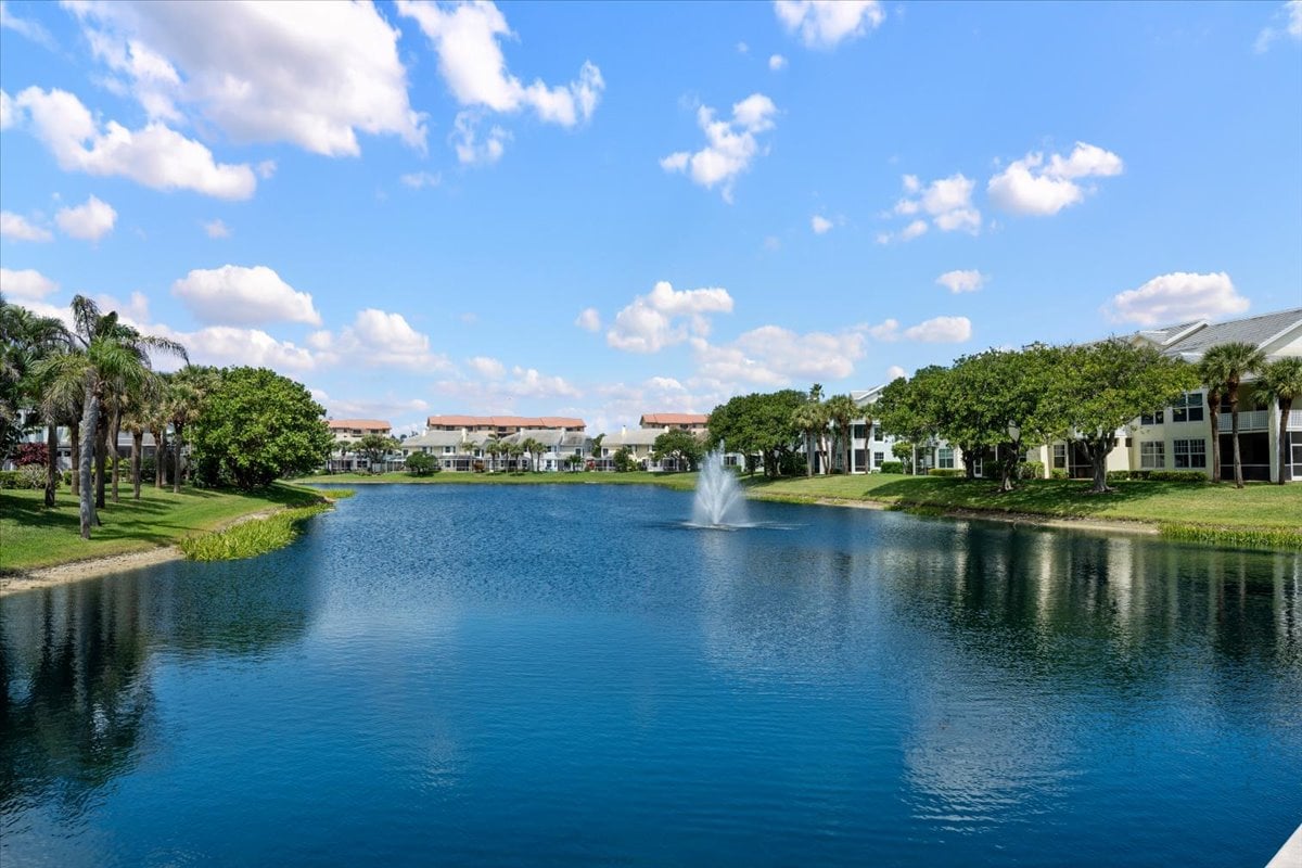 Sea Colony condos line a landscaped lake with a fountain and palm trees.