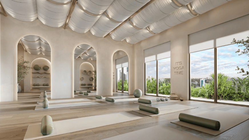 Yoga studio with arched niches, yoga mats, and floor-to-ceiling windows overlooking greenery.