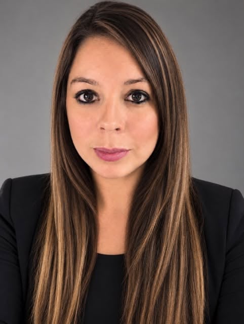 Desiree Sikes, real estate agent with long highlighted brown hair wearing a black blazer.