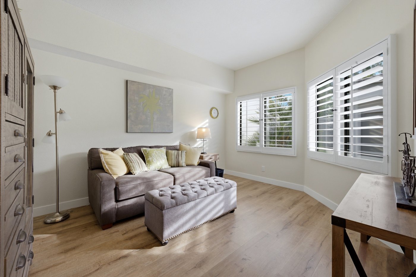 Den with grey sofa and plantation shutters at a PGA West home