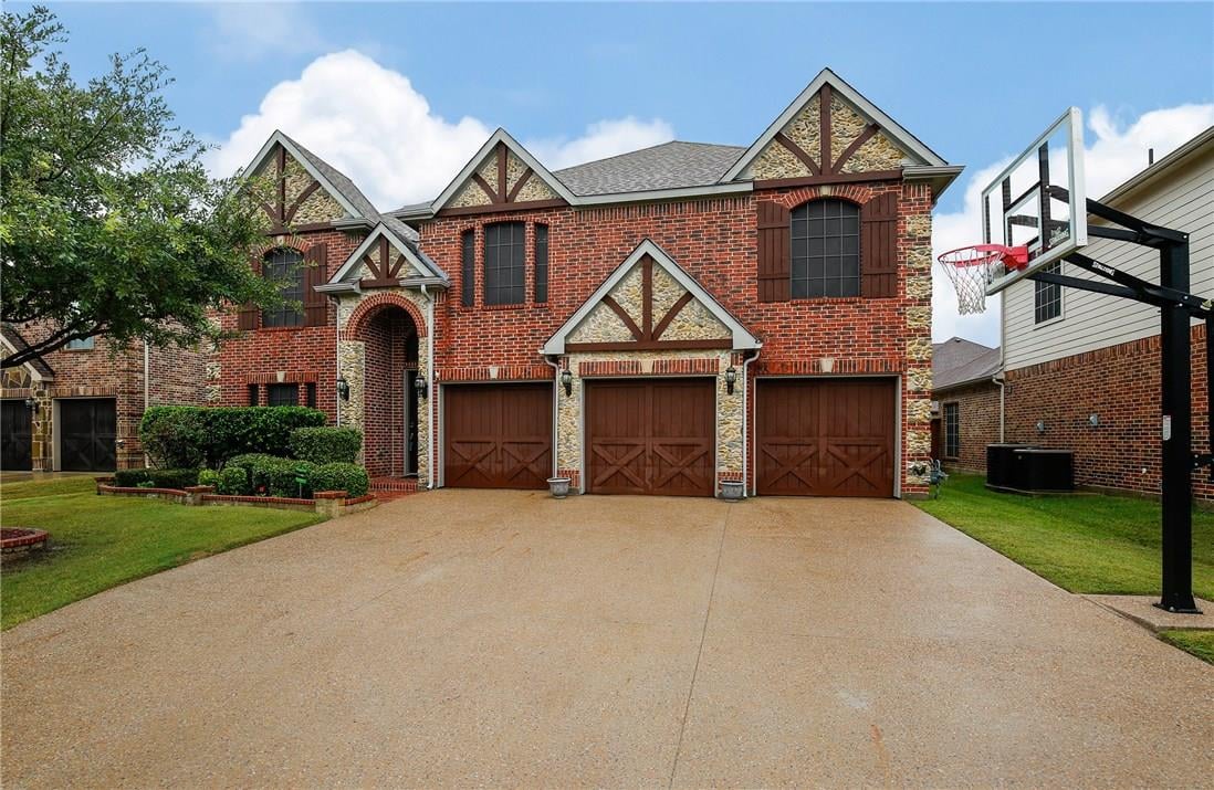 Two-story brick house with stone accents, three garage doors, and a basketball hoop by the driveway.