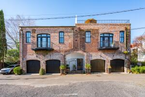 Two-story brick building with three arched garage entrances and two balconies.