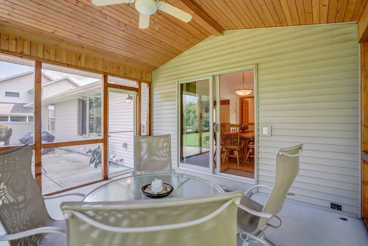 Screened-in porch with a wood ceiling, ceiling fan, and glass patio table