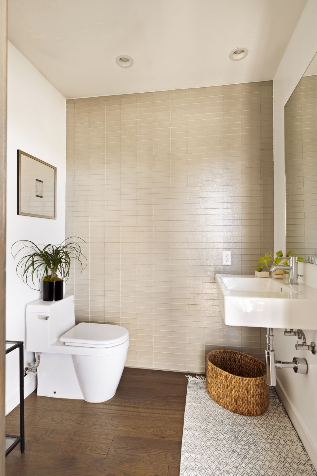 Bathroom with a beige tiled accent wall, wall-mounted sink, and patterned runner rug.