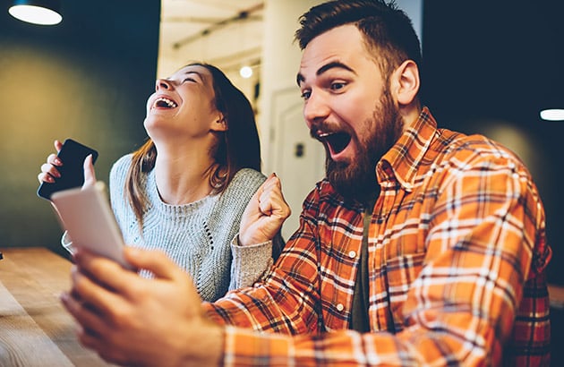 Young couple excitedly looking at a tablet indoors
