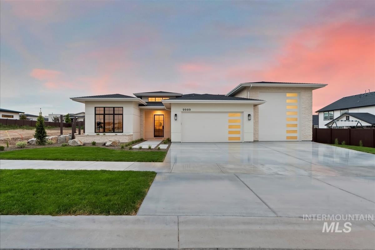 Single-level modern prairie new home with black steel windows, glass front door, and four garages