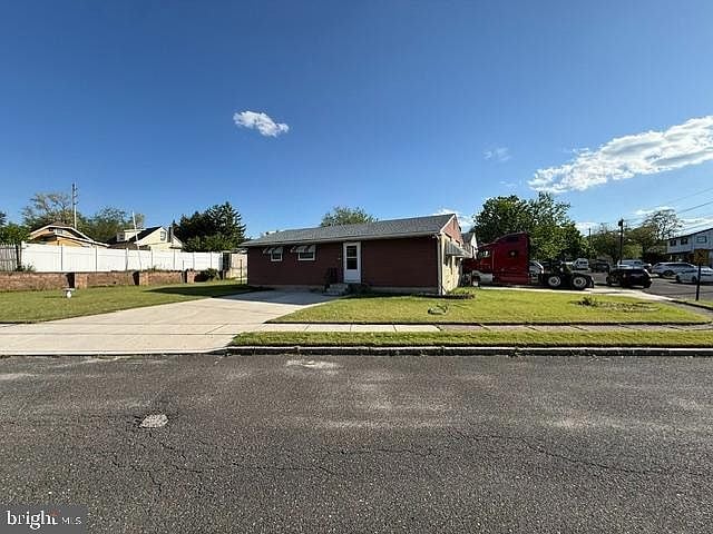Single-story brick building beside a paved driveway and lawn, with a red truck parked nearby.