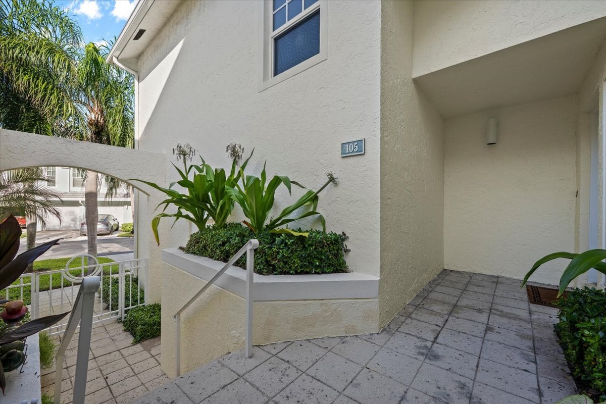 Condominium entrance marked 105, with a recessed doorway, tiled patio, and tropical planting.