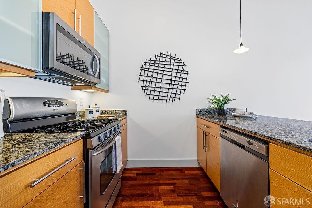 Kitchen with wood cabinets, granite counters, stainless steel appliances, and dark hardwood flooring.