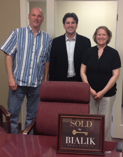 Three people pose behind a SOLD by Bialik Real Estate sign.