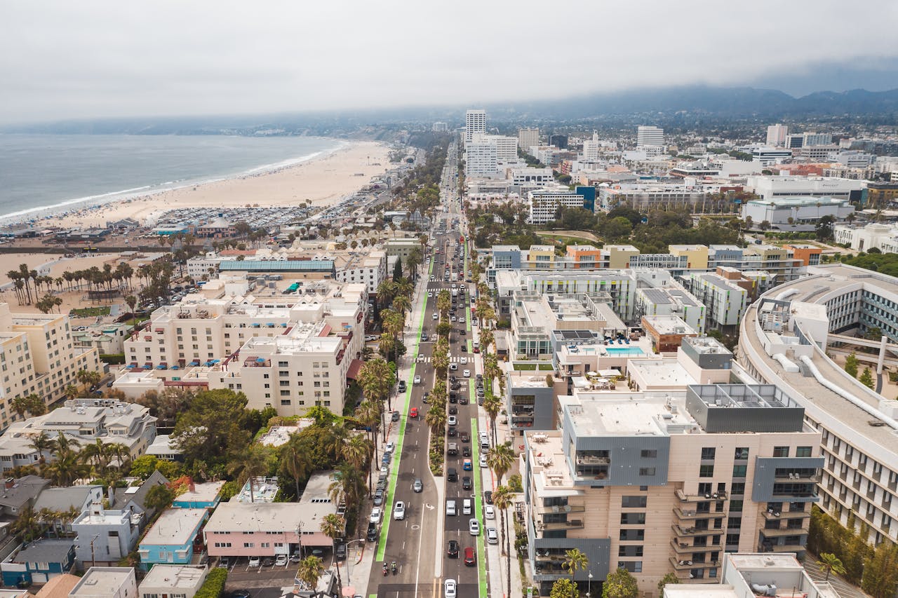 Aerial view of Santa Monica, California, with the beach, city boulevard, and Santa Monica Mountains visible in the background.
