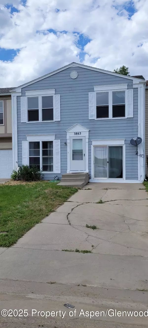 Blue two-story home with white trim, paired upper windows, and a cracked concrete driveway.